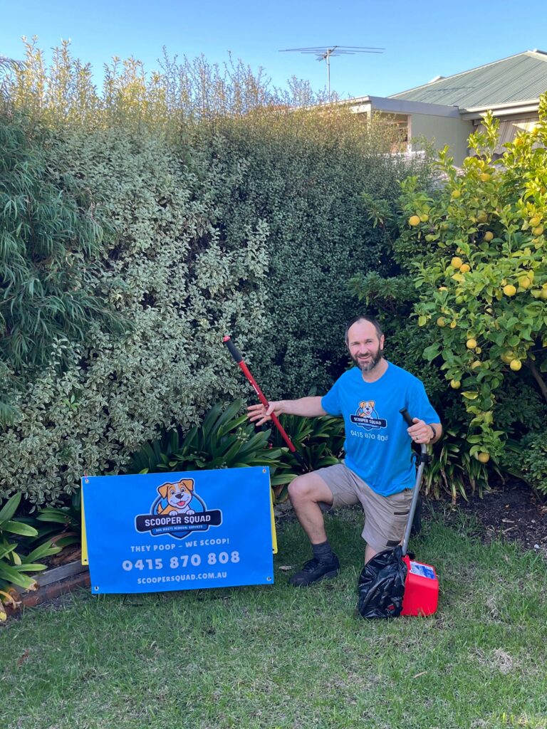 Scooper Squad owner kneeling in backyard with pooper scooper tools and yard sign